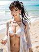 A woman in a white bikini standing on a beach.