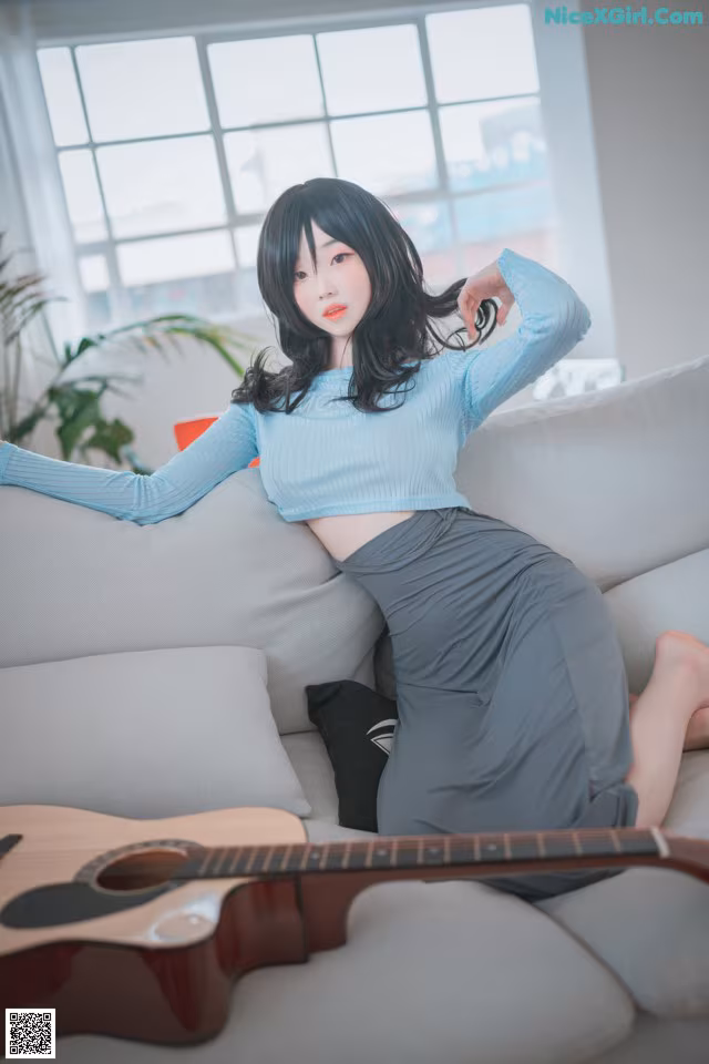 A woman sitting on a couch with a guitar.