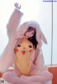 A woman in a Pikachu costume sitting on a bed.