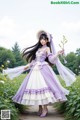 A woman in a purple and white dress standing in a field of flowers.