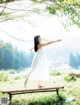 A woman in a white dress standing on a wooden bench.