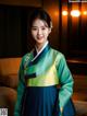 A woman in a green and blue hanbok posing for a picture.