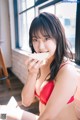 A woman in a red bikini eating an apple.