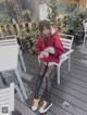 A woman sitting on a white chair wearing a red hoodie.