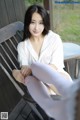 A woman sitting on a wooden bench wearing white stockings.